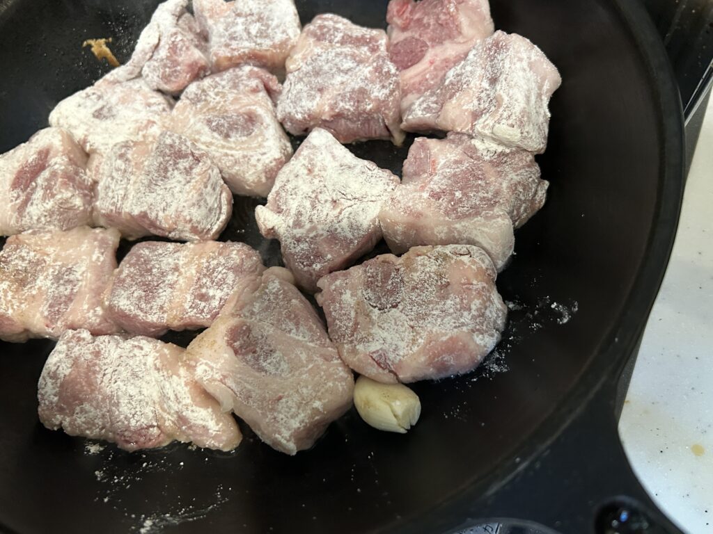 ビーフシチュー用の肉に小麦粉をまぶして焼いている様子